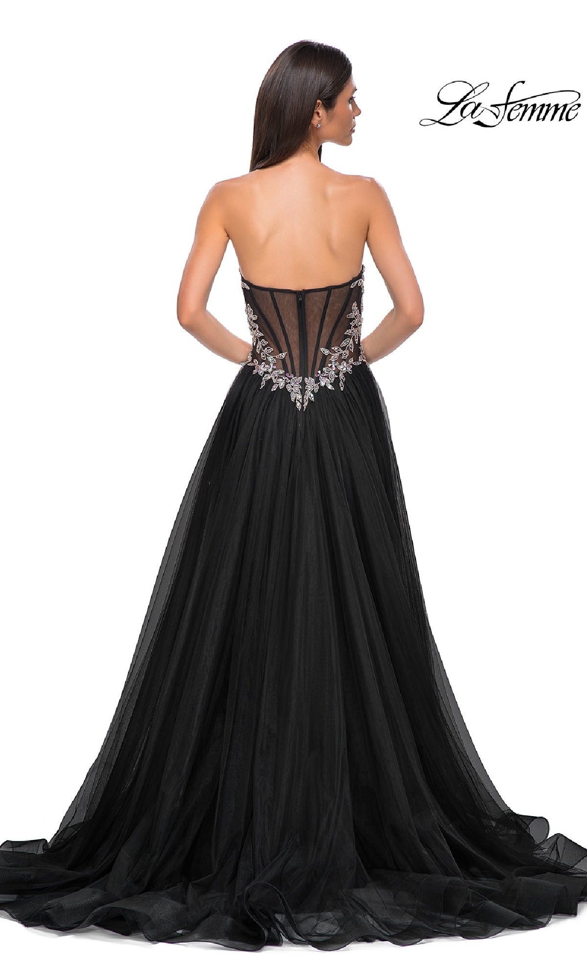 Woman showcasing the La Femme 32862 Beaded-Corset Strapless Prom Gown, featuring a beaded corset back, floral embellishments, and a floor-length tulle skirt, viewed from behind.